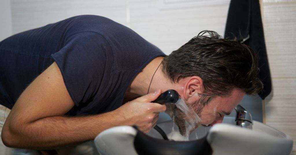 Man rinsing beard after using beard shampoo