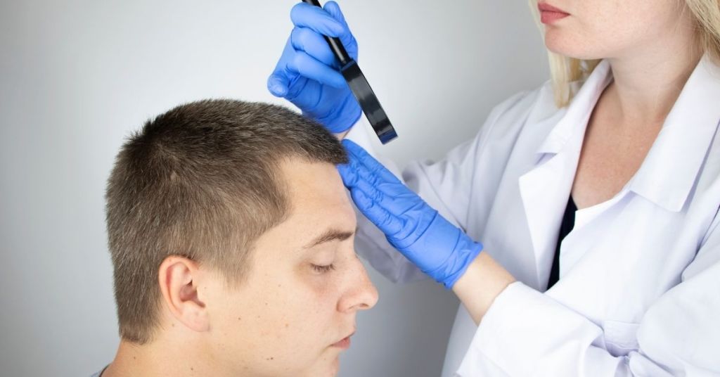 doctor examining the hair of a man who will begin microblading for alopecia