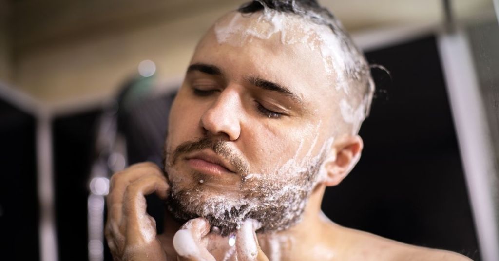 Man taking shower and using beard shampoo