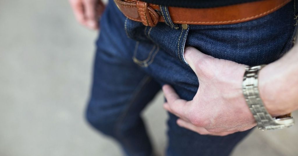 Man wearing denim pants and silver plated wrist watch