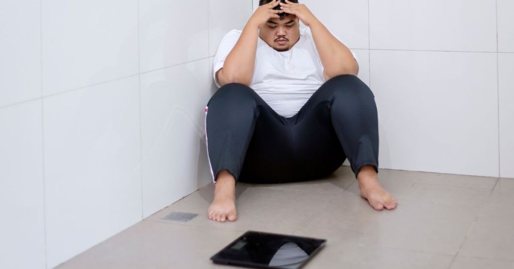 Overweight man sitting next with a Scale