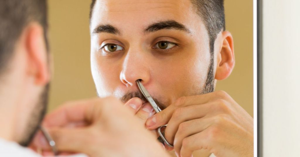 Man trimming nose hair using scissors